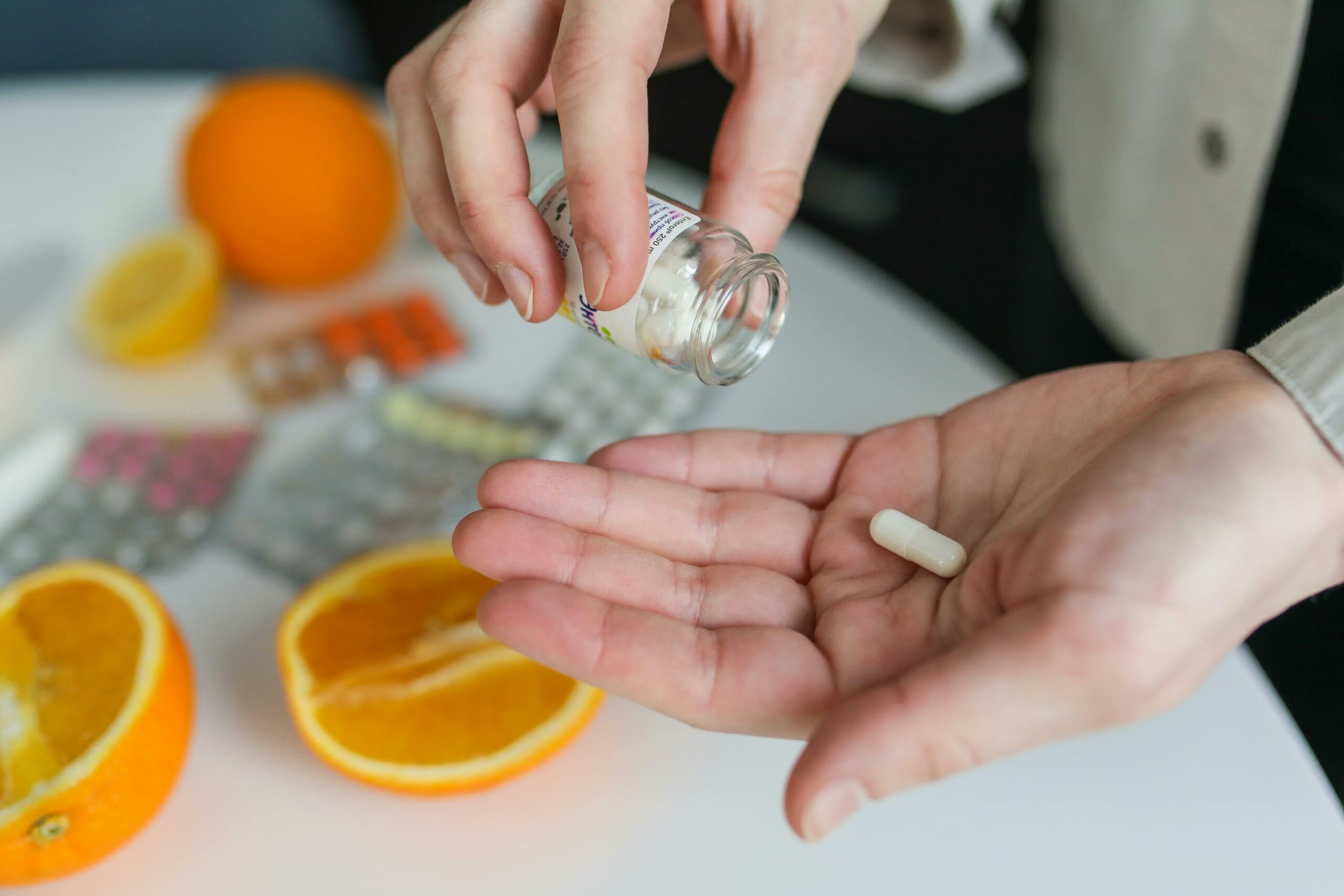 Una donna mette le pillole di Ashwagandha in un barattolo accanto alle arance, sfruttandone i benefici scientifici per la salute.